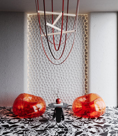  Contemporary interior featuring Kandes Salt 3D gypsum wall panels, designed with a textured organic pattern that mimics natural salt formations. The plaster wall panels are elegantly backlit, enhancing the depth and structure of the surface. Vibrant translucent red lounge chairs, a sculptural black coffee table, and a geometric pendant light complete the modern aesthetic. This high-end decorative wall paneling solution is perfect for luxury interiors, offering a sophisticated yet bold design statement for 